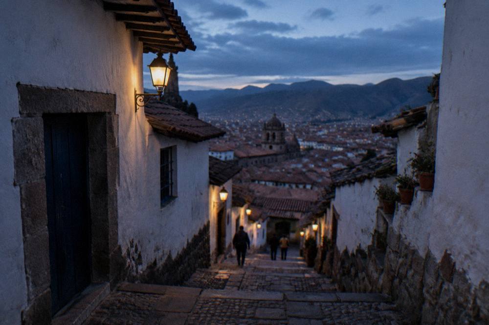 A narrow cobblestone lane in the San Blas district of Cusco lined with whitewashed walls