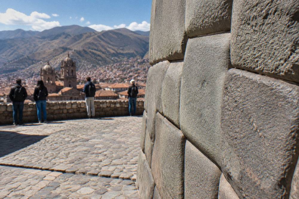 Visitors looking at a finely fitted Inca stone wall in central Cusco