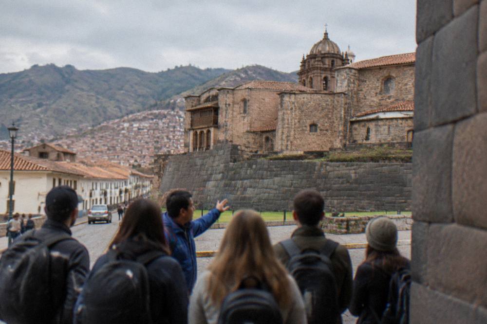A group of travellers gathered around a guide at a Cusco street corner