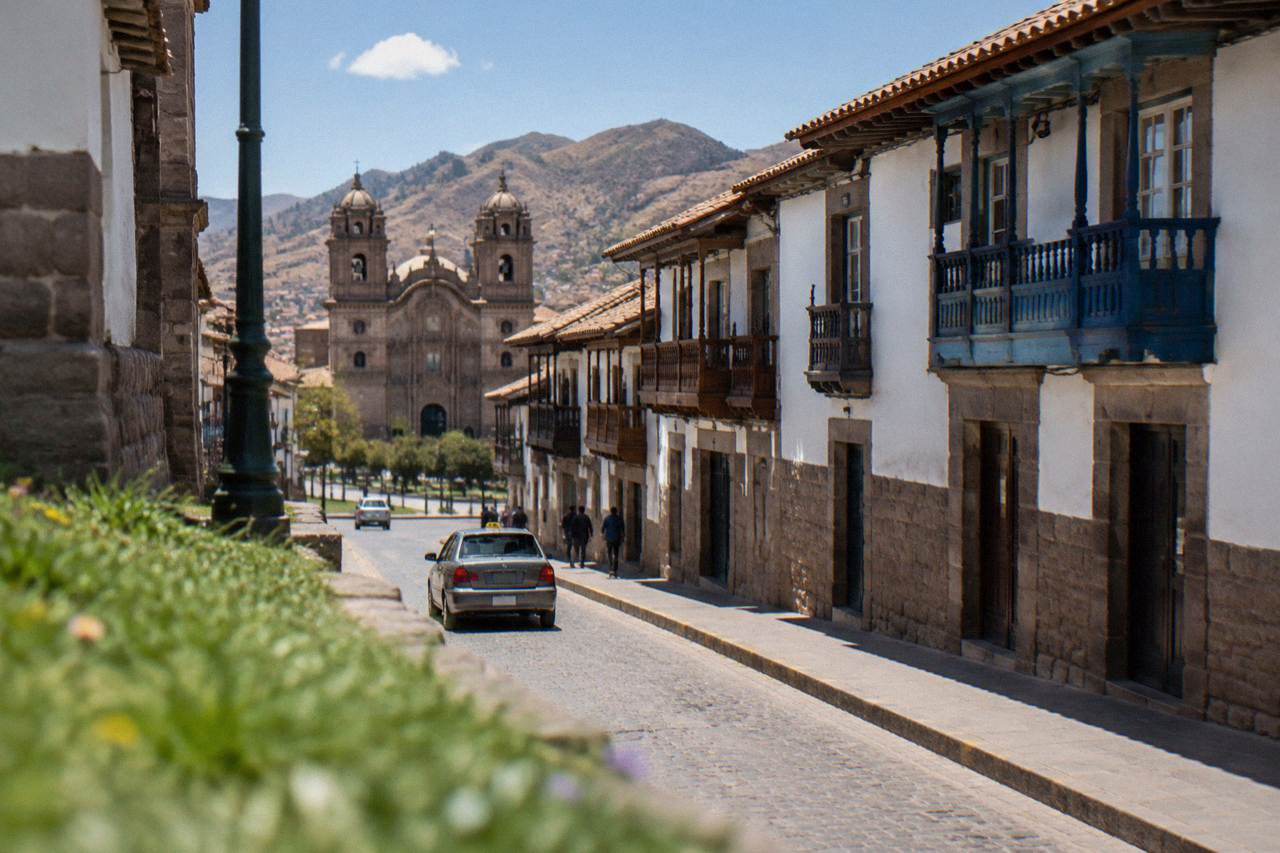 A narrow stone street in Cusco with colonial balconies and a taxi passing below