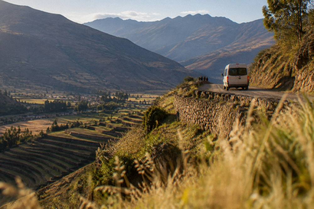 A minibus and a stone-walled road above the terraces of the Sacred Valley