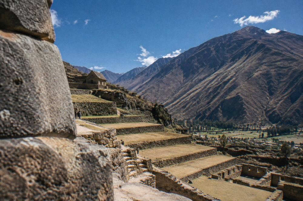 A dry-season view over Inca terraces with deep blue sky and thin clouds over Andean peaks