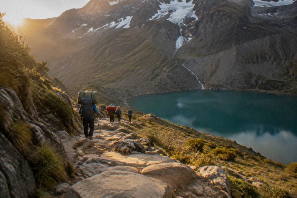 Porters in coloured clothing carrying packs along a high mountain path