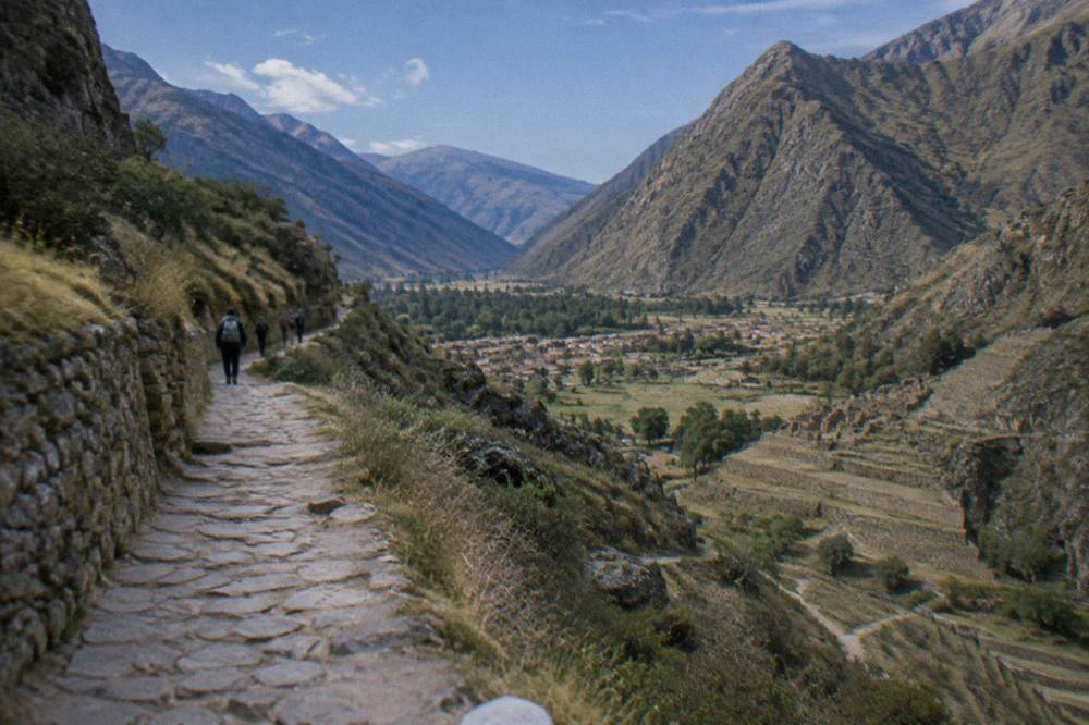 A high Andean valley under a clear blue sky with a stone path crossing the slope