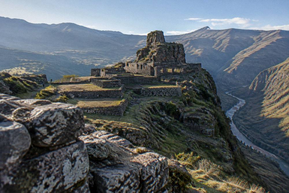 Terraced stone ruins on a mountain ridge above a winding river gorge