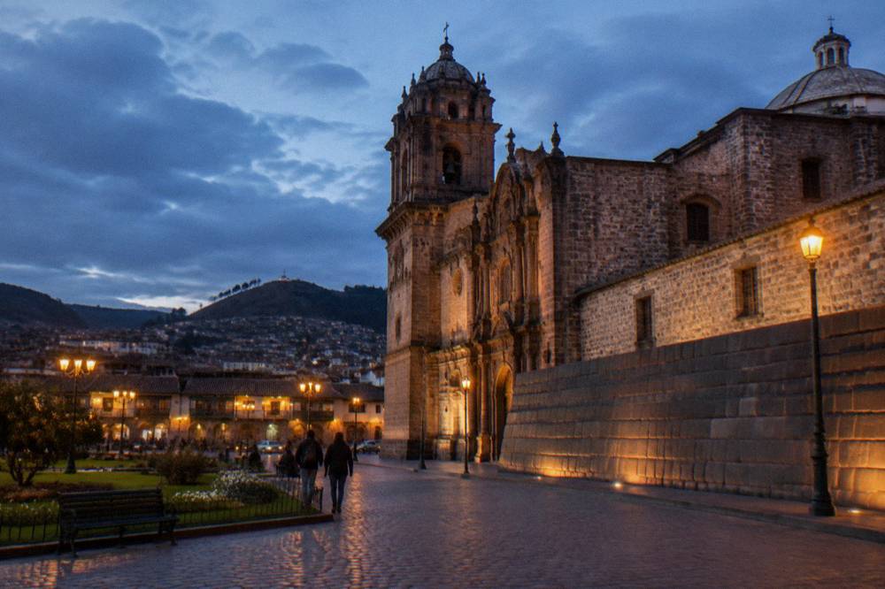 Smooth Inca stone wall of Qorikancha beneath a colonial church facade