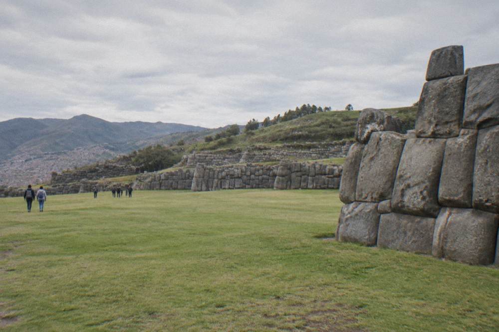 Open grassy esplanade of Sacsayhuaman with rolling green hills behind it