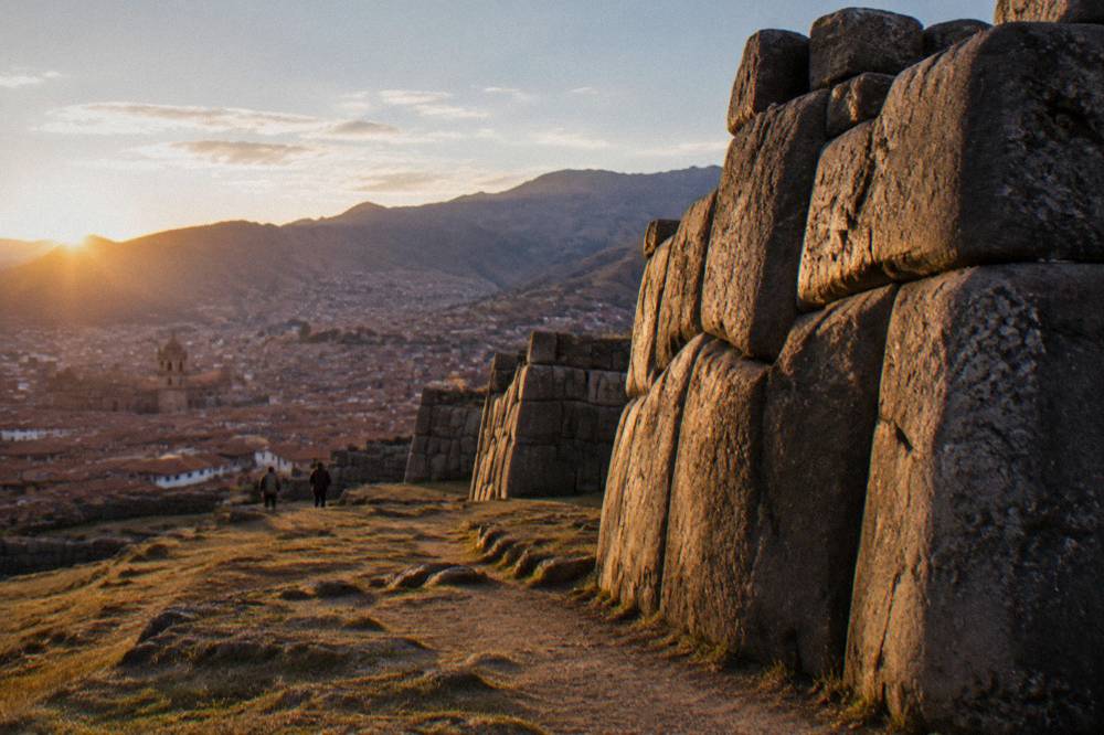 Cold clear sunrise over red tiled rooftops of Cusco with mountains behind