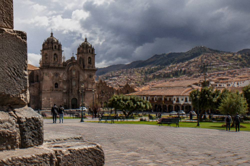 Rain clouds gathering over red-tiled rooftops and hillsides above a high Andean city