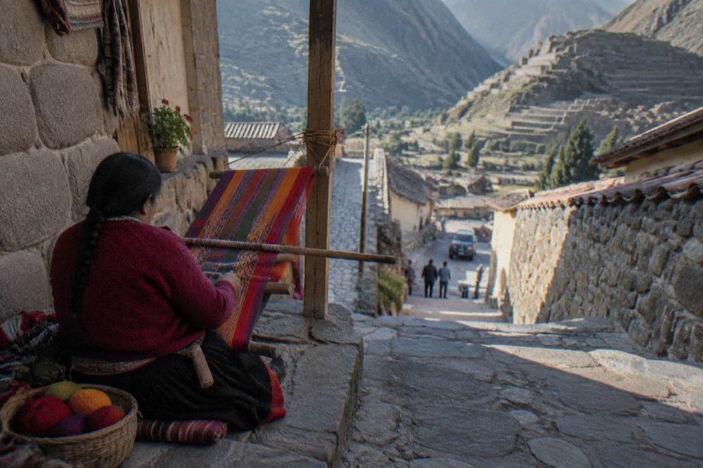 Quechua weaver working a colourful textile on a traditional loom