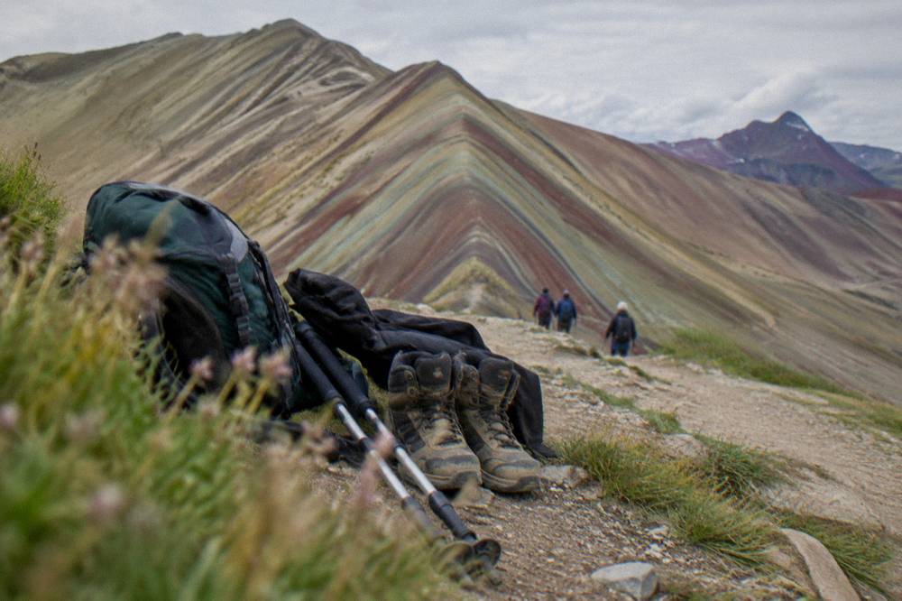 Trekking gear and boots laid out beside a pack in mountain daylight