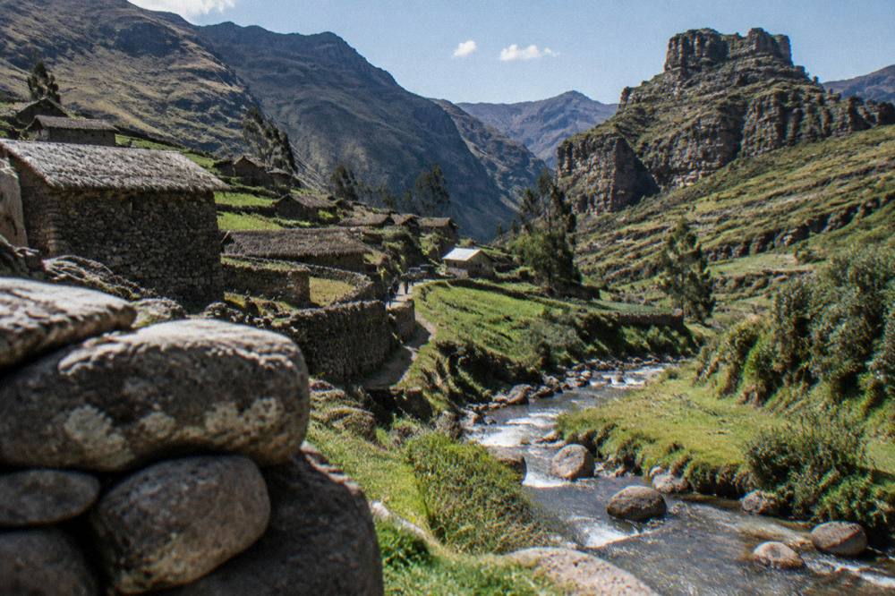 Small stone village beside a stream in a green high Andean valley