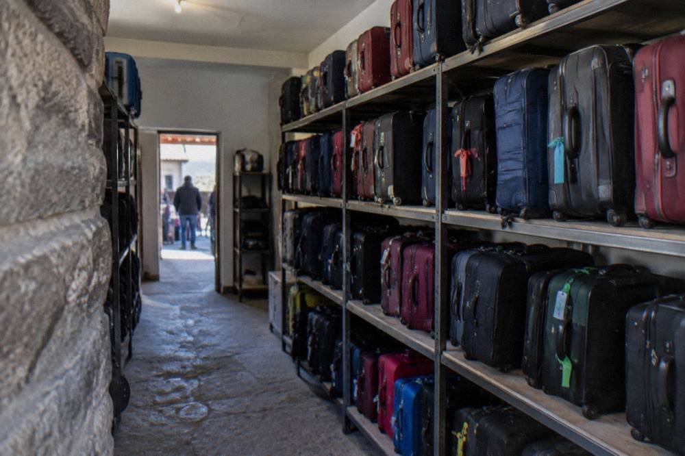 A hotel storage room with labelled suitcases lined up on shelves