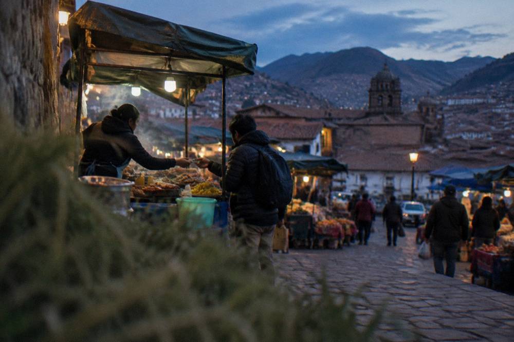 A vendor handing change in soles to a customer at a busy Cusco food market stall