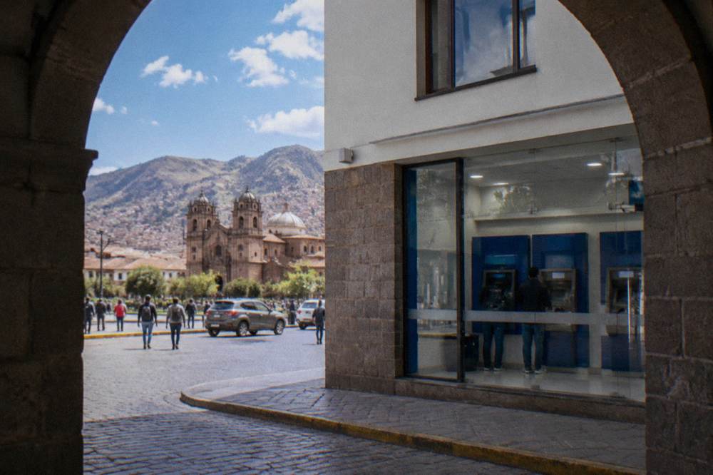 A bank branch facade with an ATM lobby on a busy street near the Plaza de Armas in Cusco