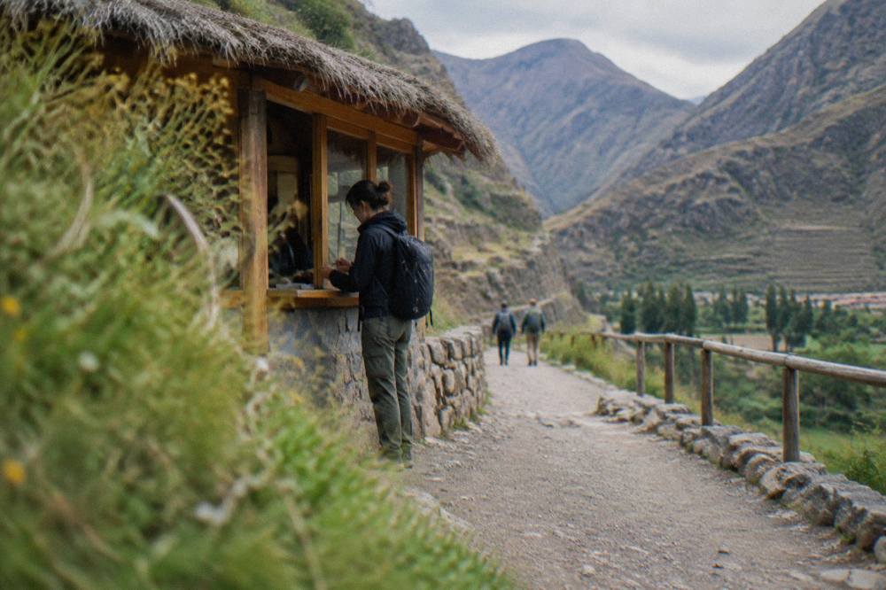 A visitor paying an entrance fee in cash at a rural Andean trailhead booth
