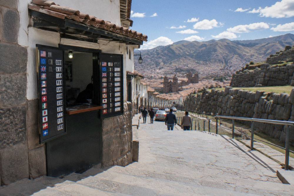 A currency exchange booth with rate boards on a pedestrian street in central Cusco