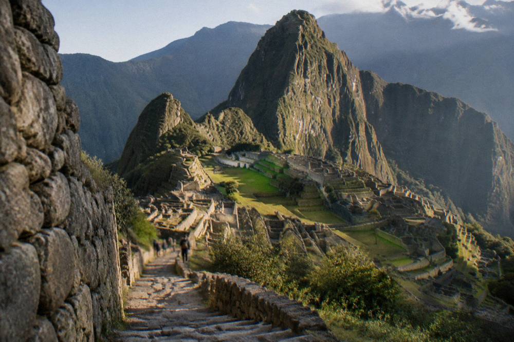 The stone terraces of Machu Picchu with the green Huayna Picchu peak behind under morning light