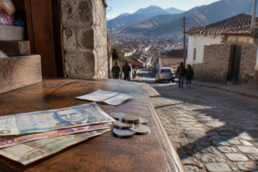 Peruvian sol banknotes and coins on a wooden counter beside a small paper receipt