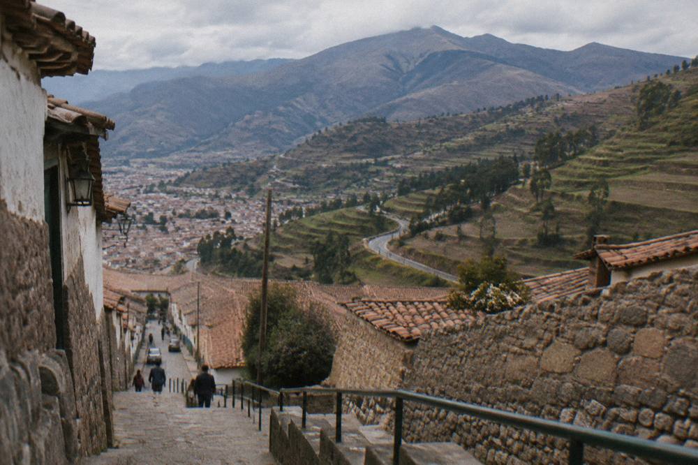 An open Andean valley landscape with terraced hillsides and a winding road below mountains