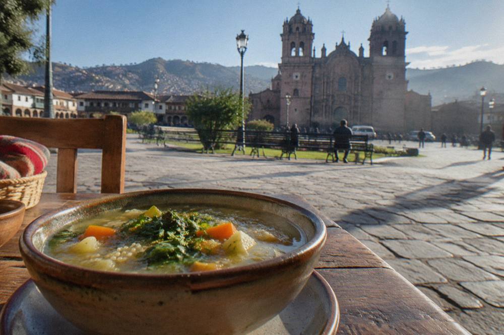 A bowl of quinoa soup with vegetables on a rustic table