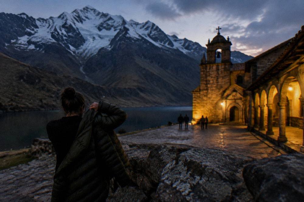 Traveller adding a jacket at dusk beside a lit colonial arcade in Cusco