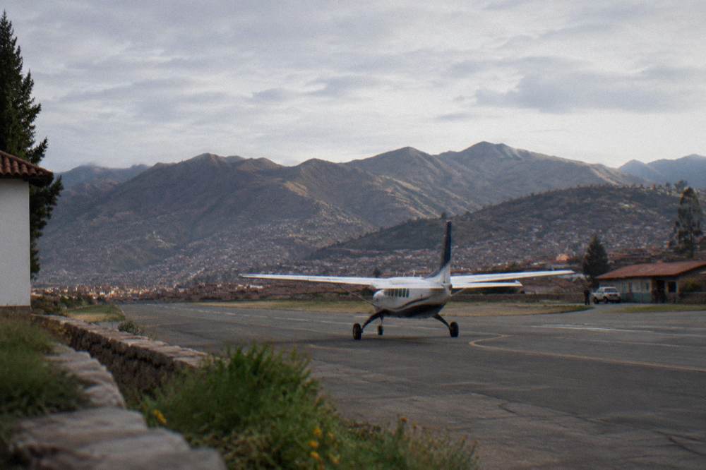 A small aircraft on a runway surrounded by mountains under morning light