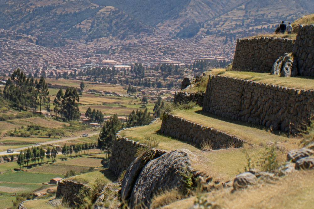 Ancient stone terraces built into a hillside above a valley of fields