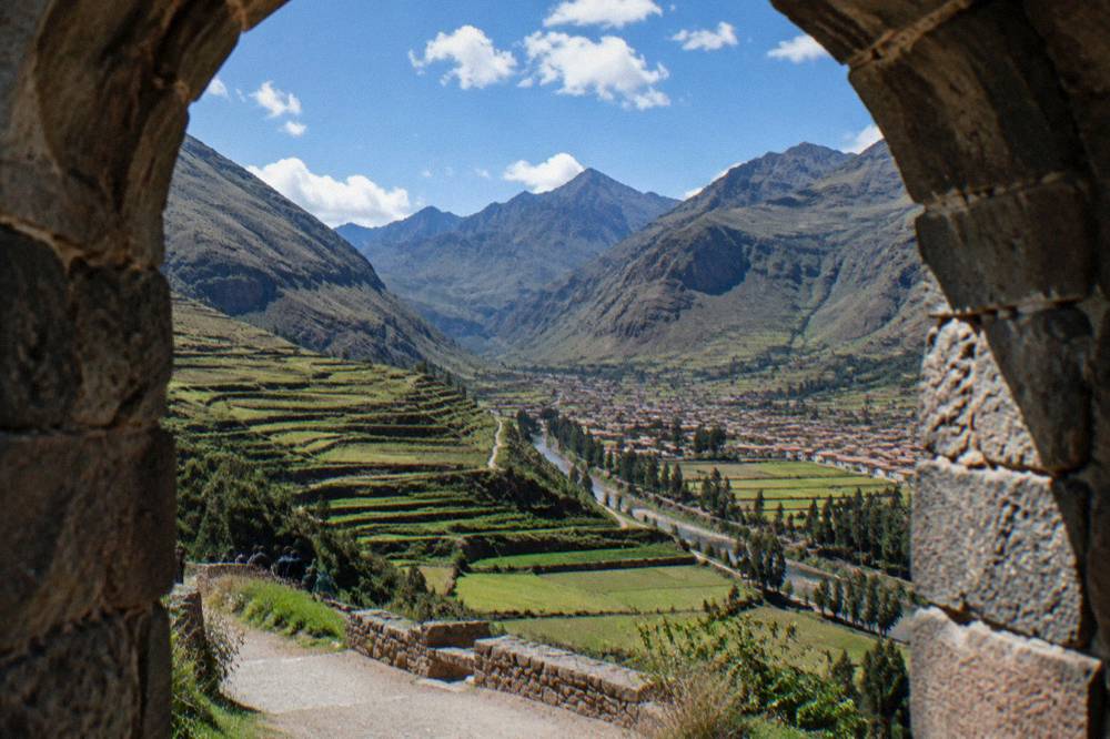 Terraced green valley fields below Andean peaks with a village at the base