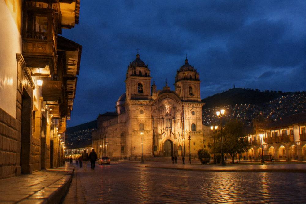 Lit stone street with balconied buildings at night in a historic centre