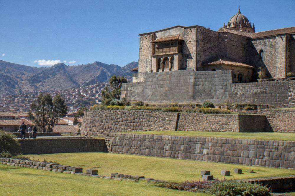 Terraced stone walls of a hilltop Inca site above Cusco under a wide blue sky