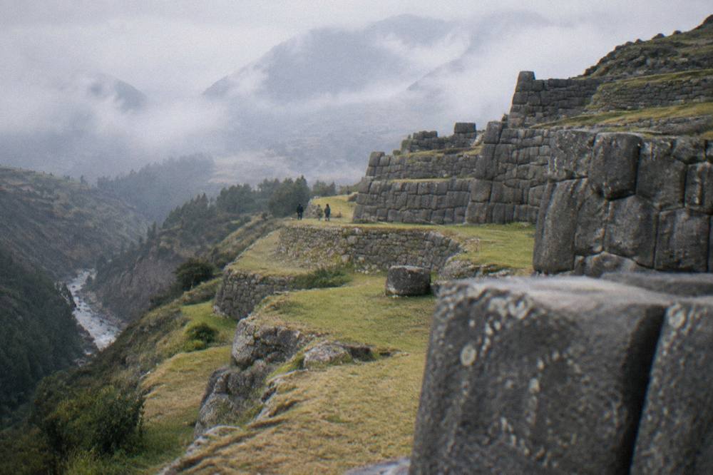 Stone terraces of a mountain citadel rising above a river gorge in morning mist