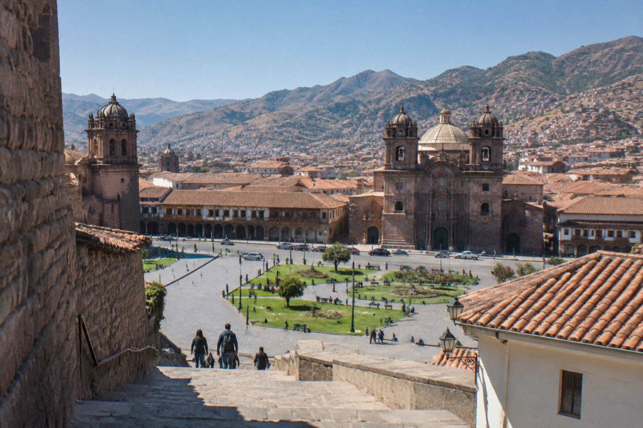 Cusco rooftops and church domes under a clear sky with Andean hills behind