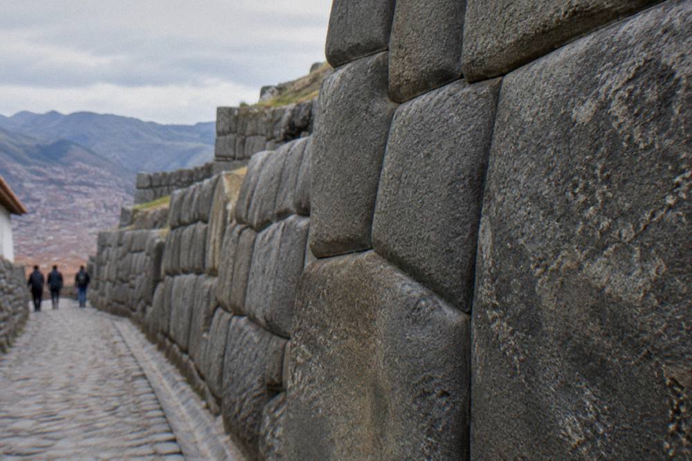 An Inca stone wall with precisely fitted polygonal blocks on a narrow Cusco street