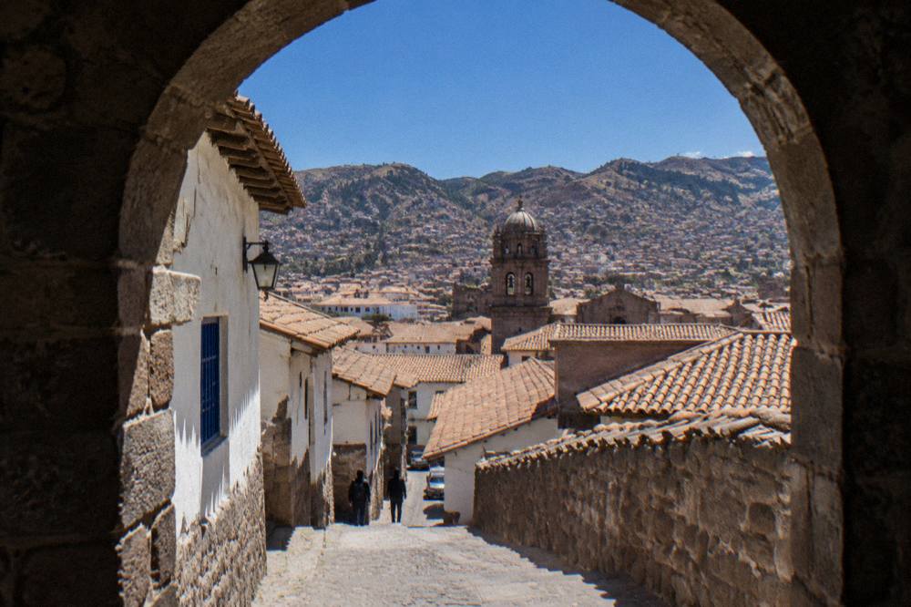 Cusco rooftops under a deep blue dry-season sky with hillsides beyond