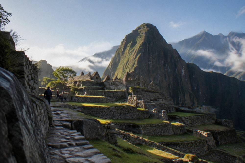 Terraced stone terraces of Machu Picchu with a green peak rising behind them