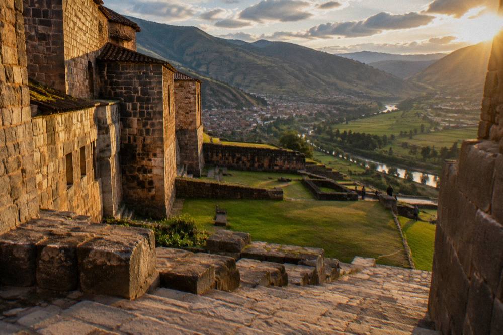 Green Andean valley with a river and terraced fields under scattered cloud