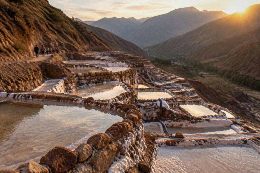 Salt evaporation pans terraced down a hillside in warm afternoon light