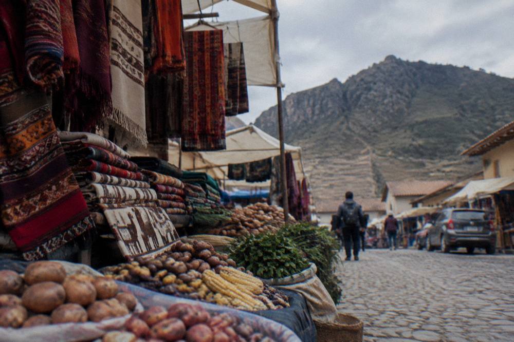 A local market stall with woven textiles and stacked produce