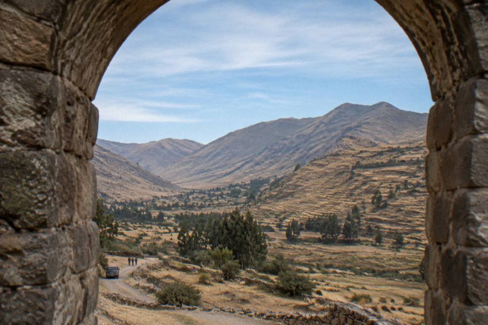 Wide view of a dry Andean valley with terraces on the far slope under a clear sky